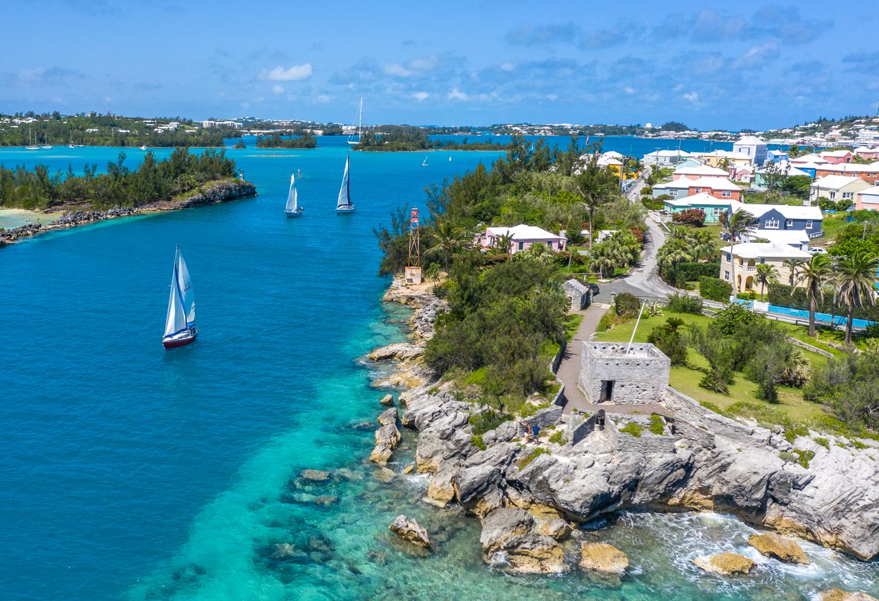 Sailboats racing in Bermuda harbor with colorful waterfront buildings