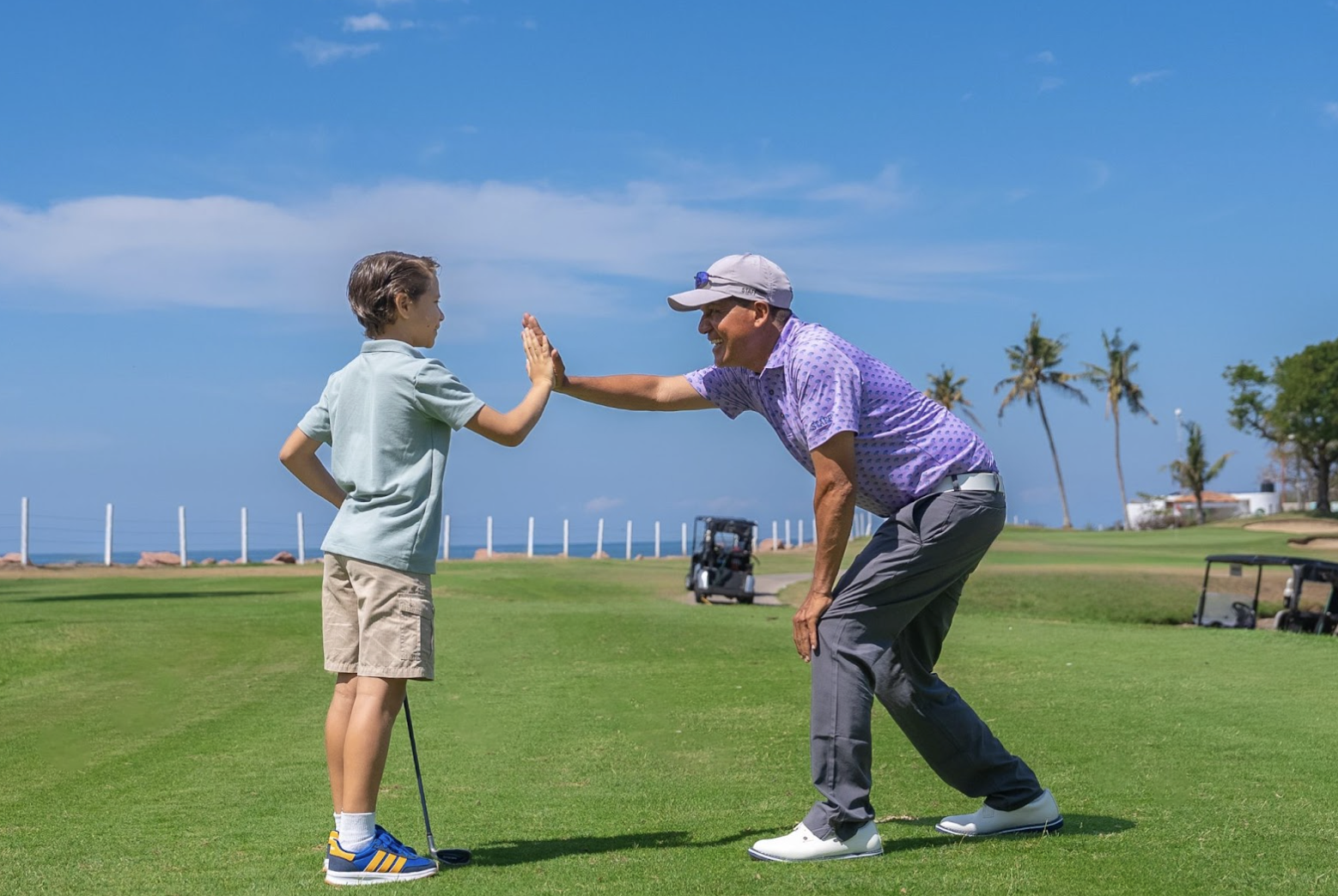 Father and son high-fiving on golf course at Velas Vallarta in Puerto Vallarta Mexico