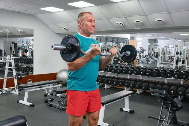 older man lifting weights in gym
