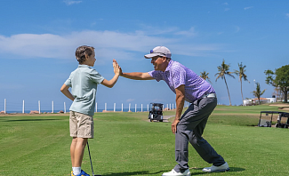Father and son high-fiving on golf course at Velas Vallarta in Puerto Vallarta Mexico