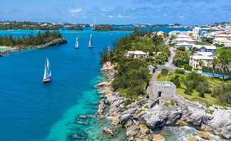 Sailboats racing in Bermuda harbor with colorful waterfront buildings