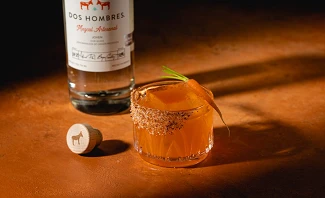 Dos Hombres Mezcal bottle with Sweet Lips cocktail featuring chili salt rim and carrot garnish