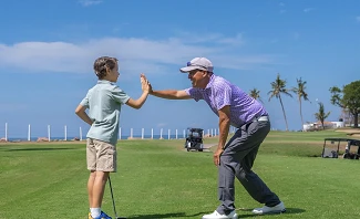 Father and son high-fiving on golf course at Velas Vallarta in Puerto Vallarta Mexico